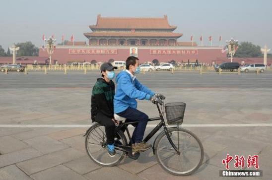 11月3日，北京大气扩散条件转差，空气污染指数持续攀升。据悉，北京已于2日傍晚发布空气重污染黄色预警。图为一对青年佩戴口罩骑车经过北京天安门广场。 中新社记者崔楠摄
